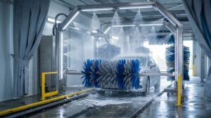 A clean, modern tunnel car wash interior with bright professional lighting and water mist.